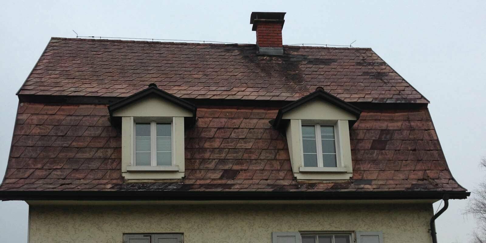 Toit mansardé avant la rénovation de toiture à l’aide de tuiles PREFA, revêtement de la lucarne inclus