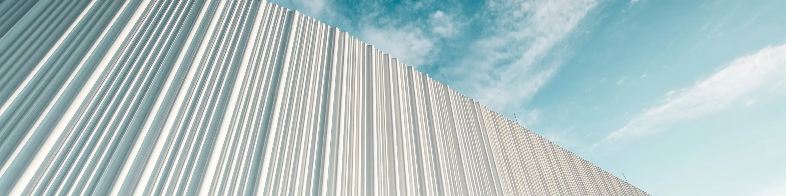 Une architecture à couper le souffle avec une façade en aluminium PREFA blanche dans le parc d’activités Walter Business Park près de Vienne. La façade, composée de profils extrudés sur mesure, crée grâce à son caractère ondulant et fluide un jeu fascinant d’ombre et de lumière. Trois formes de profils différentes apportent une profondeur exceptionnelle et confèrent au bâtiment une esthétique à la fois claire sur le plan stylistique et résolument dynamique. La surface PREFA, durable et résistante aux intempéries, associe une esthétique moderne à une perfection fonctionnelle – un véritable point fort de l’architecture de façade contemporaine, qui rend visibles la qualité architecturale et la sophistication technique.