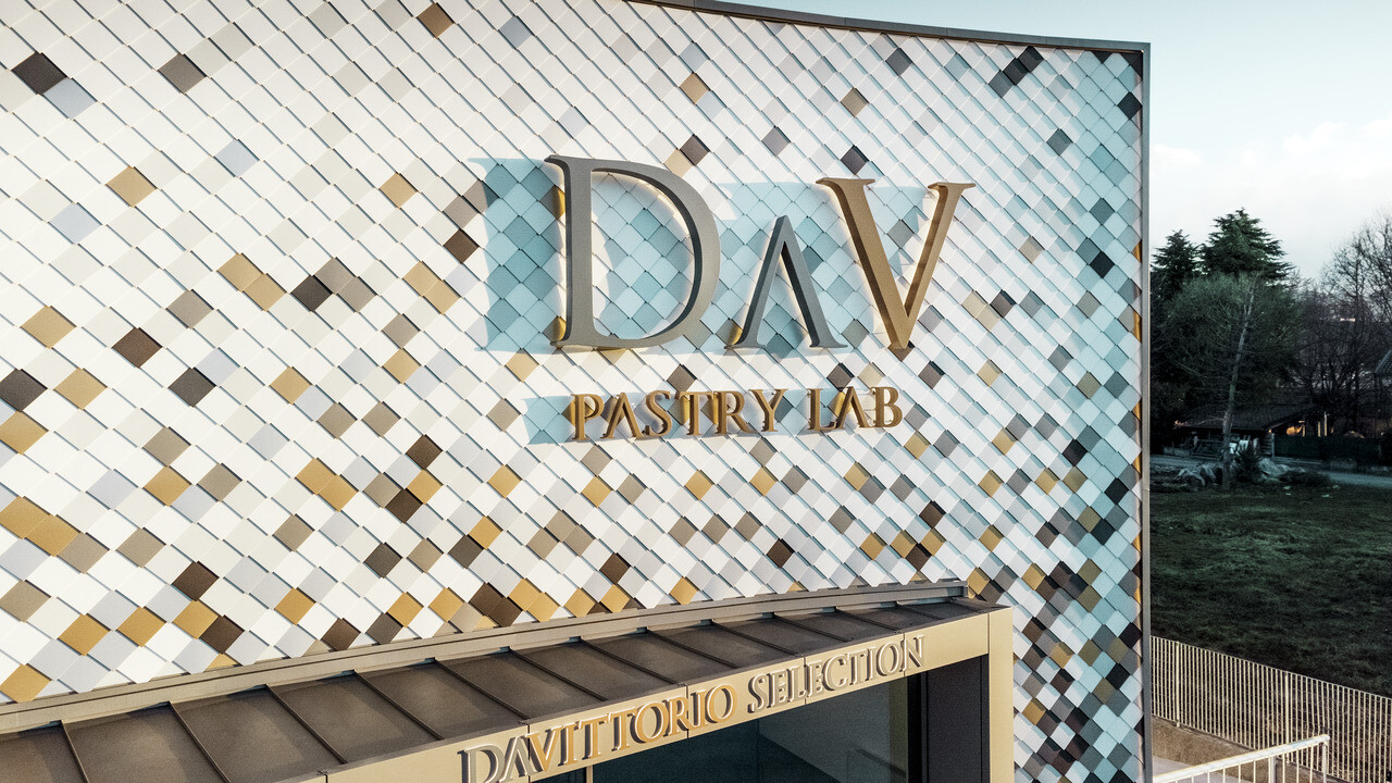 Bâtiment d'entreprise DAV Pastry Lab de Bergame avec façade mouchetée avec le losange de façade dans les couleurs P.10 brun, bronze, P.10 gris sombre, mayagold, aluminium naturel, P.10 blanc Prefa et P.10 blanc pur. 