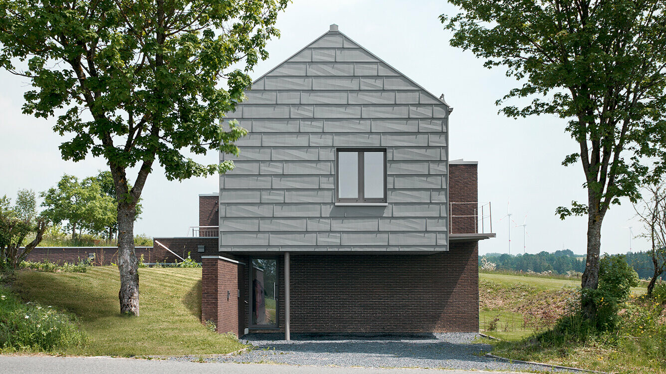 Ansicht des Bed & Breakfast Level600 im belgischen Dorf Hünningen bei Büllingen von der anderen Seite der Straße, links und rechts davon steht ein Baum.