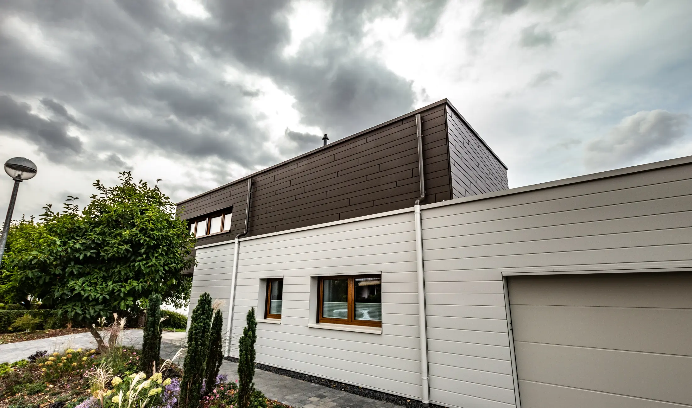 Habillage de façade d’un garage avec les Sidings PREFA à l’horizontale en blanc, avec embranchement d’évacuation.