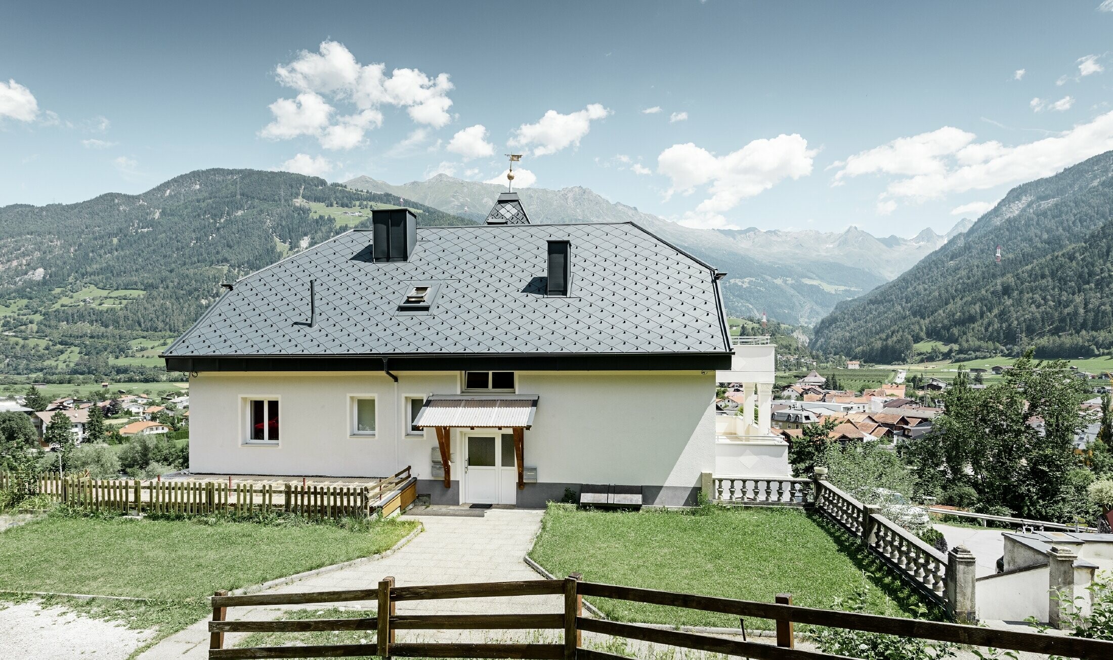 Felsenhaus mit Turm und einem Aluminiumdach in anthrazit mit einer Pizzeria im Erdgeschoss