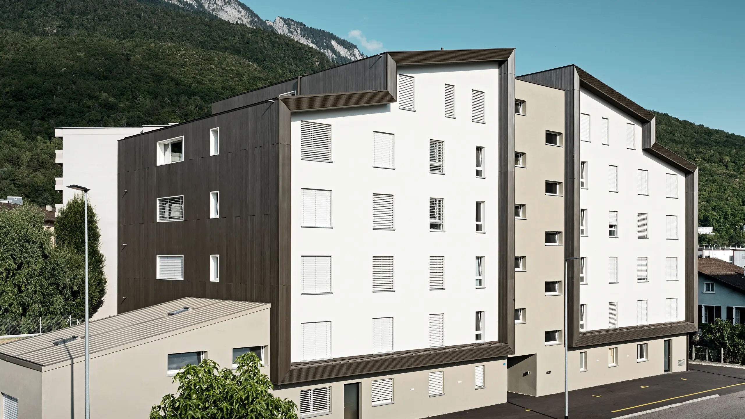 La façade du complexe résidentiel Les Dailles a été largement recouverte de l'impressionnant profil triangle PREFA en bronze. Le toit du bâtiment a été recouvert de PREFALZ en bronze.