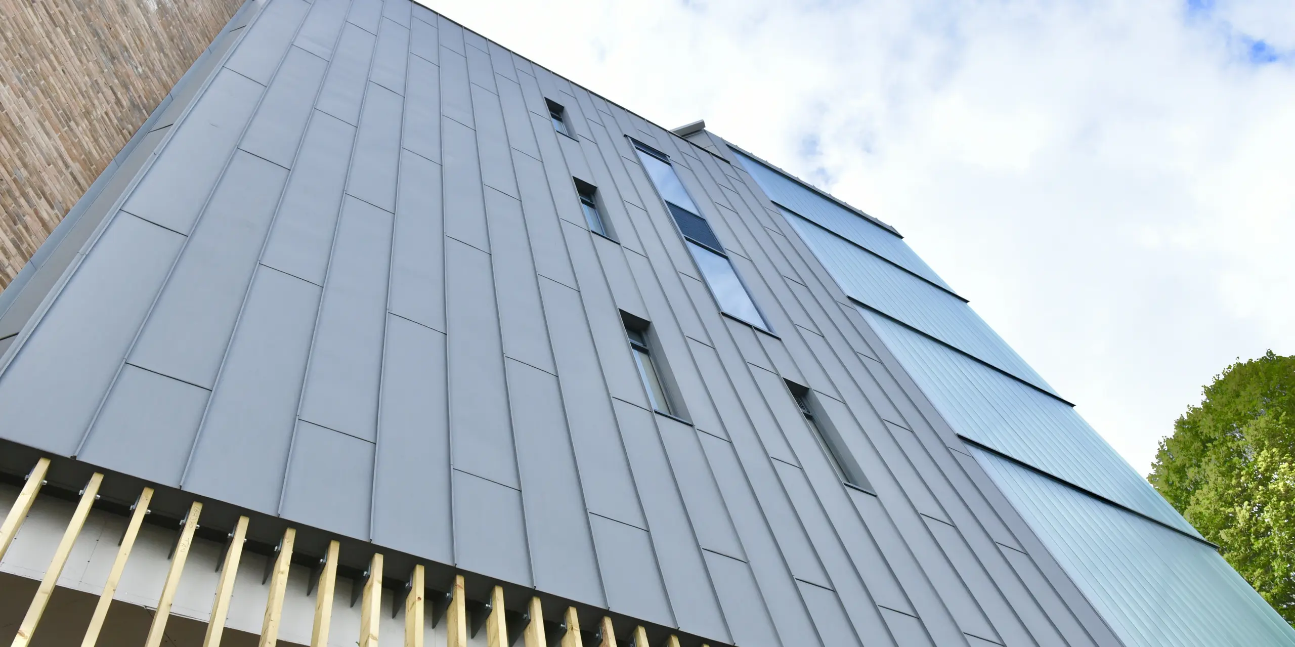Vue détaillée du bardage à joint debout PREFALZ en gris quartz au North Regional College. Le traitement précis de l'aluminium souligne le caractère durable et moderne de la façade, qui s'intègre harmonieusement dans l'architecture globale.
