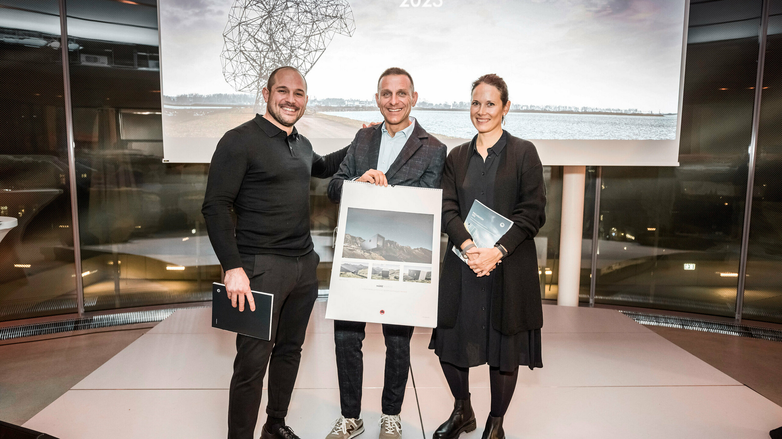 Ein Teil der teilnehmenden Architekten, Spengler und PREFA Landesgesellschaften auf der Bühne mit dem PREFARENZEN Kalender in der Hand.