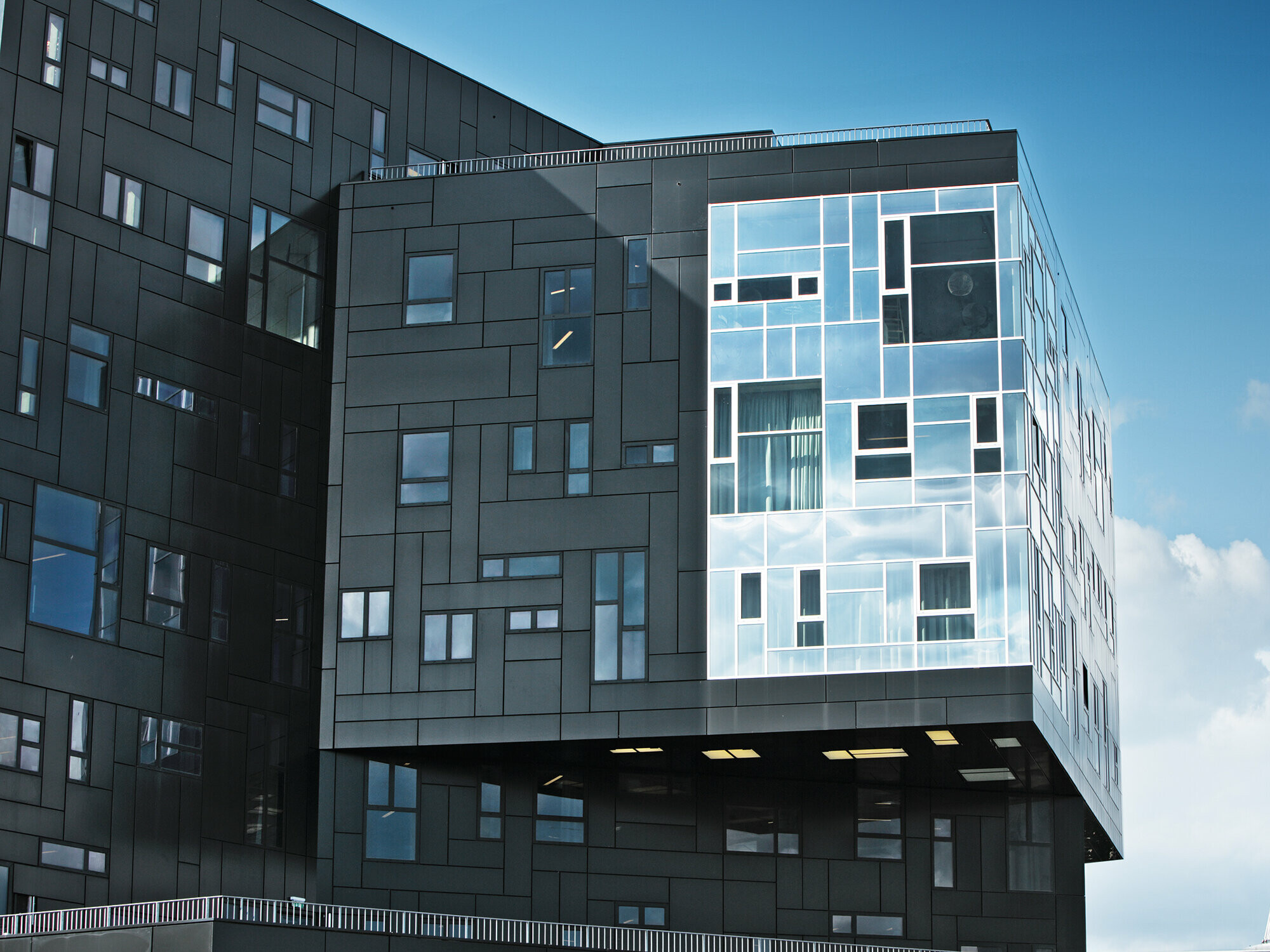 Aufnahme der WU Executive Academy mit Fokus auf die PREFA Aluminium Verbundplattenfassade in Tiefschwarz und den glänzenden Fensterabschnitt.