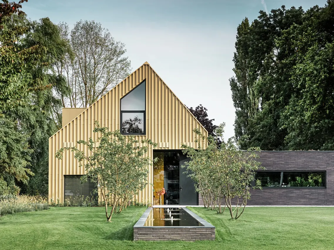 Vue de face de la maison. Les produits en aluminium  PREFA dans les couleurs beige savane et anthracite sont particulièrement efficaces en milieu rural.