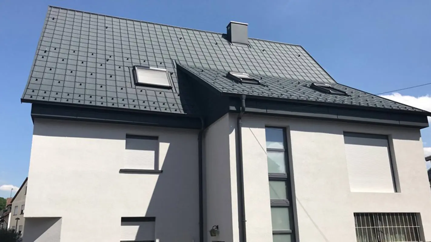 Rénovation d’un toit à deux pans à l’aide de tuiles PREFA, façade blanche