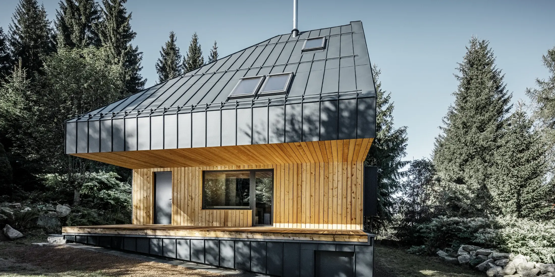Maison individuelle architecturale en forêt, l'imposante toiture a été habillée de joint debout en aluminium PREFALZ de couleur anthracite. La sous-face ainsi que la façade sont habillées de panneaux en bois.