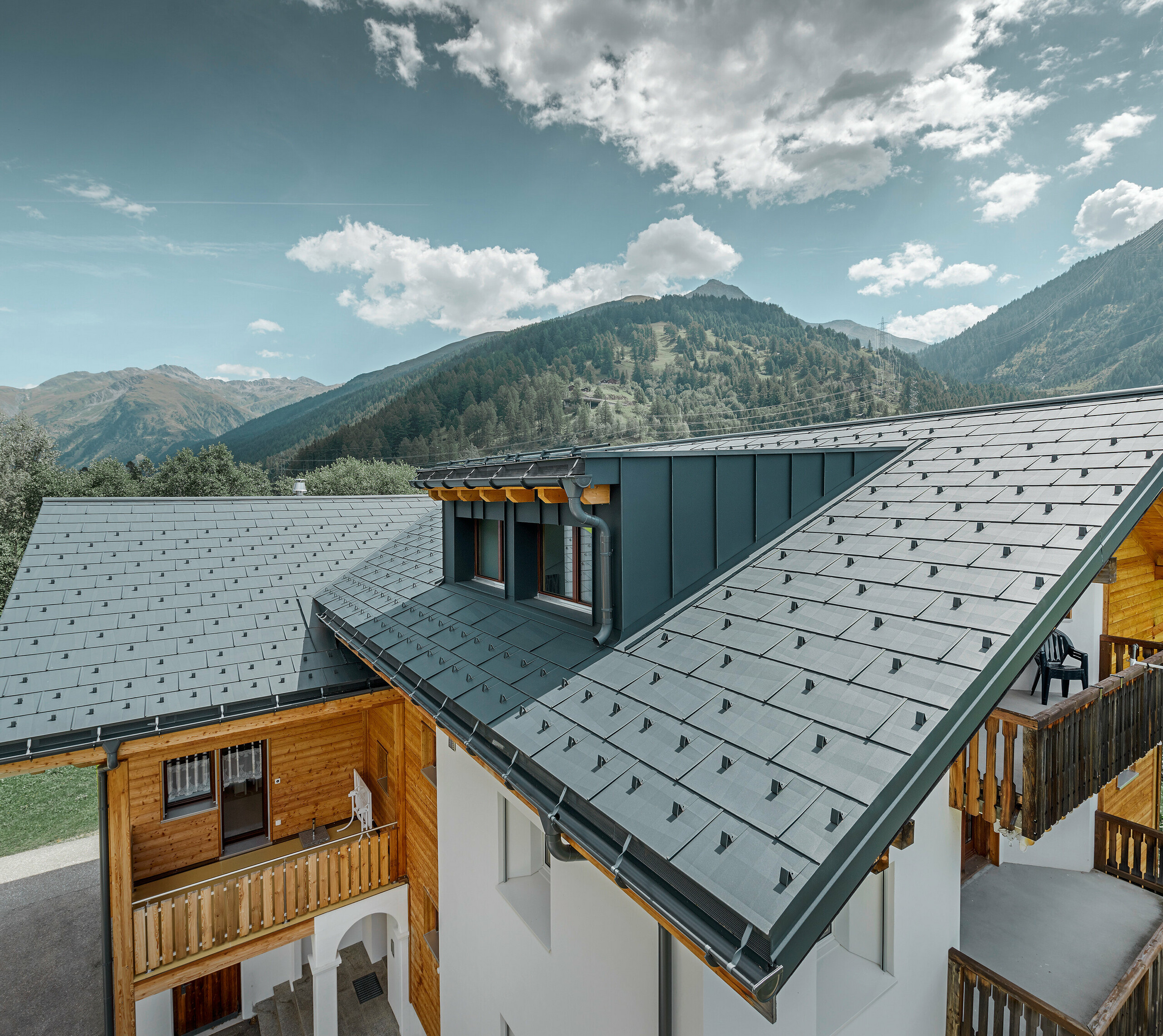 Bâtiment d’habitation rénové avec toit à deux pans et lucarne ; la rénovation de la toiture a été réalisée avec le panneau de toiture FX.12 PREFA couleur anthracite.