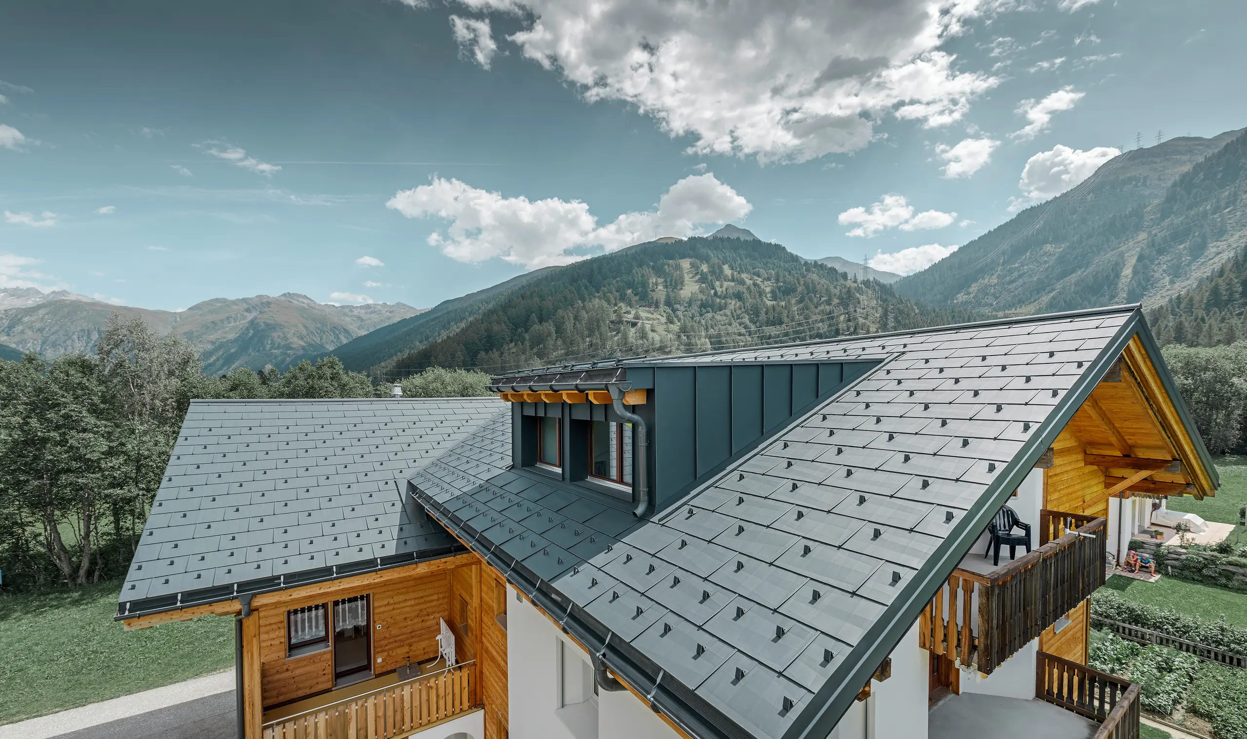 Bâtiment d’habitation rénové avec toit à deux pans et lucarne ; la rénovation de la toiture a été réalisée avec le panneau de toiture FX.12 PREFA couleur anthracite.