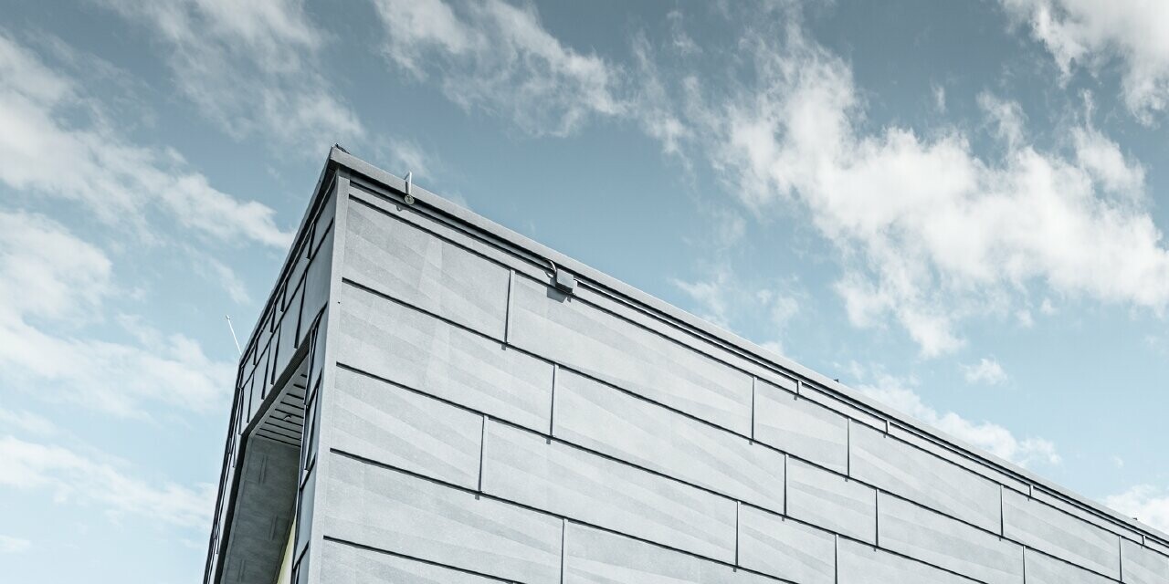 Maison individuelle moderne avec toit à deux pans sans avancée de toit ; l’étage supérieur a été habillé avec le panneau de façade couleur gris pierre de PREFA.