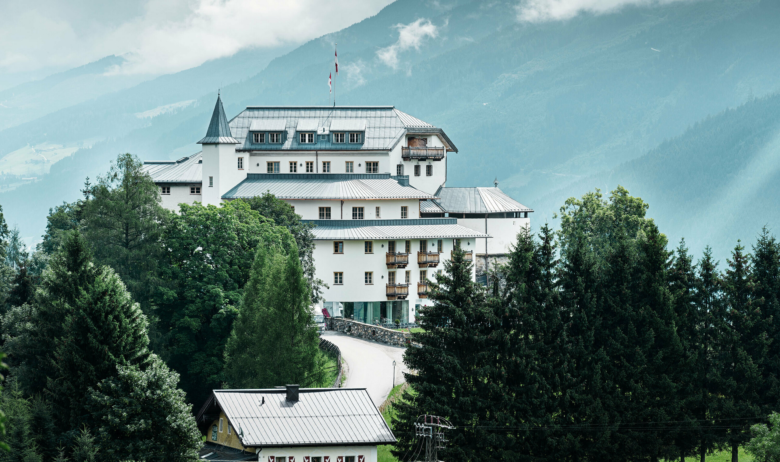 Schloss Mittersill umgeben von Bäumen und Bergen mit einem neu sanierten Prefalz Dach in steingrau