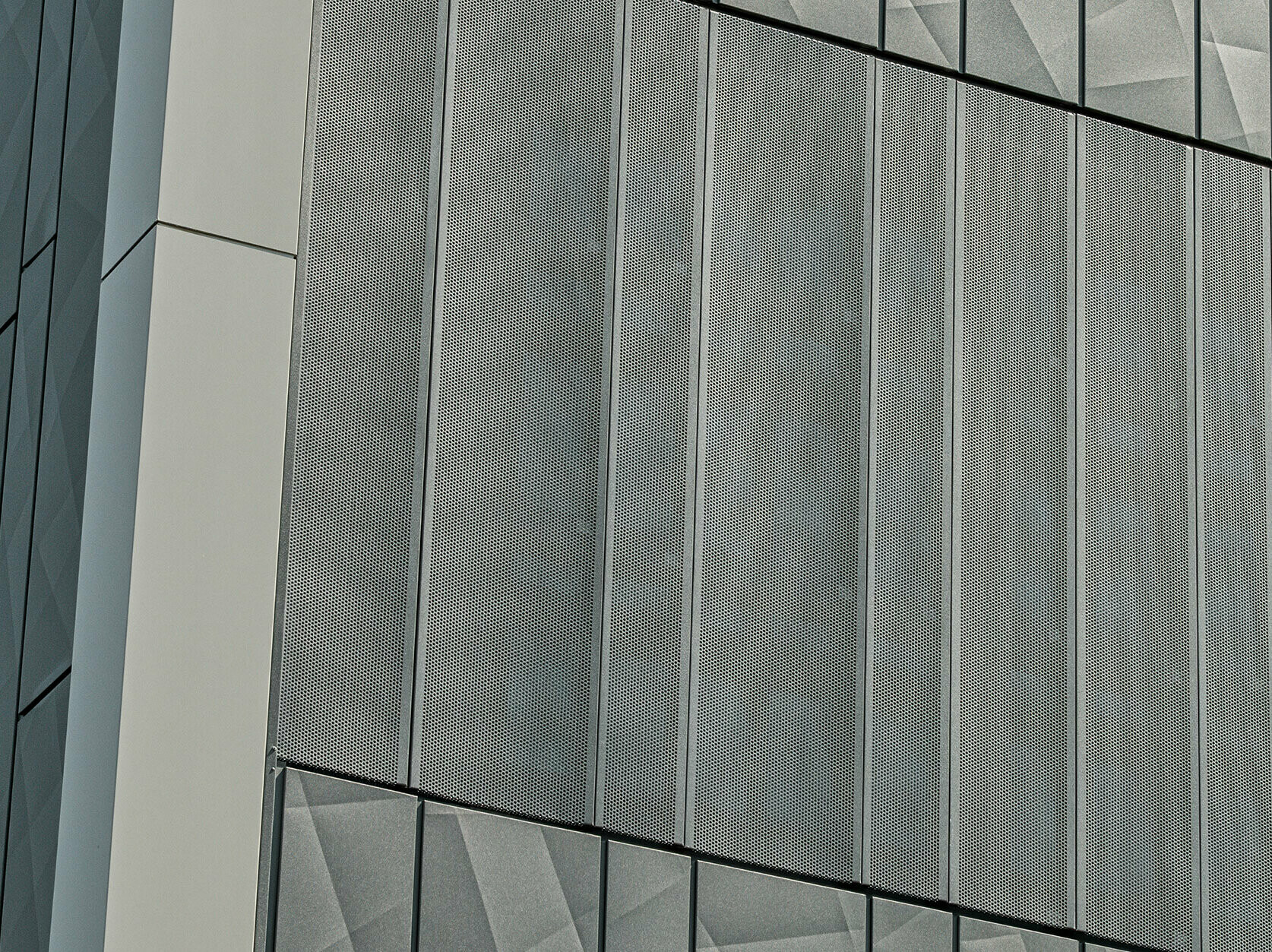 Vue de la façade d'un magasin Eurospar à Rohrbach avec des bardages PREFA Siding.X et des bardages perforés de couleur anthracite. Les éléments Siding.X présentent un motif de joints géométrique vivant, tandis que les bardages perforés offrent une structure moderne et perméable à l'air.