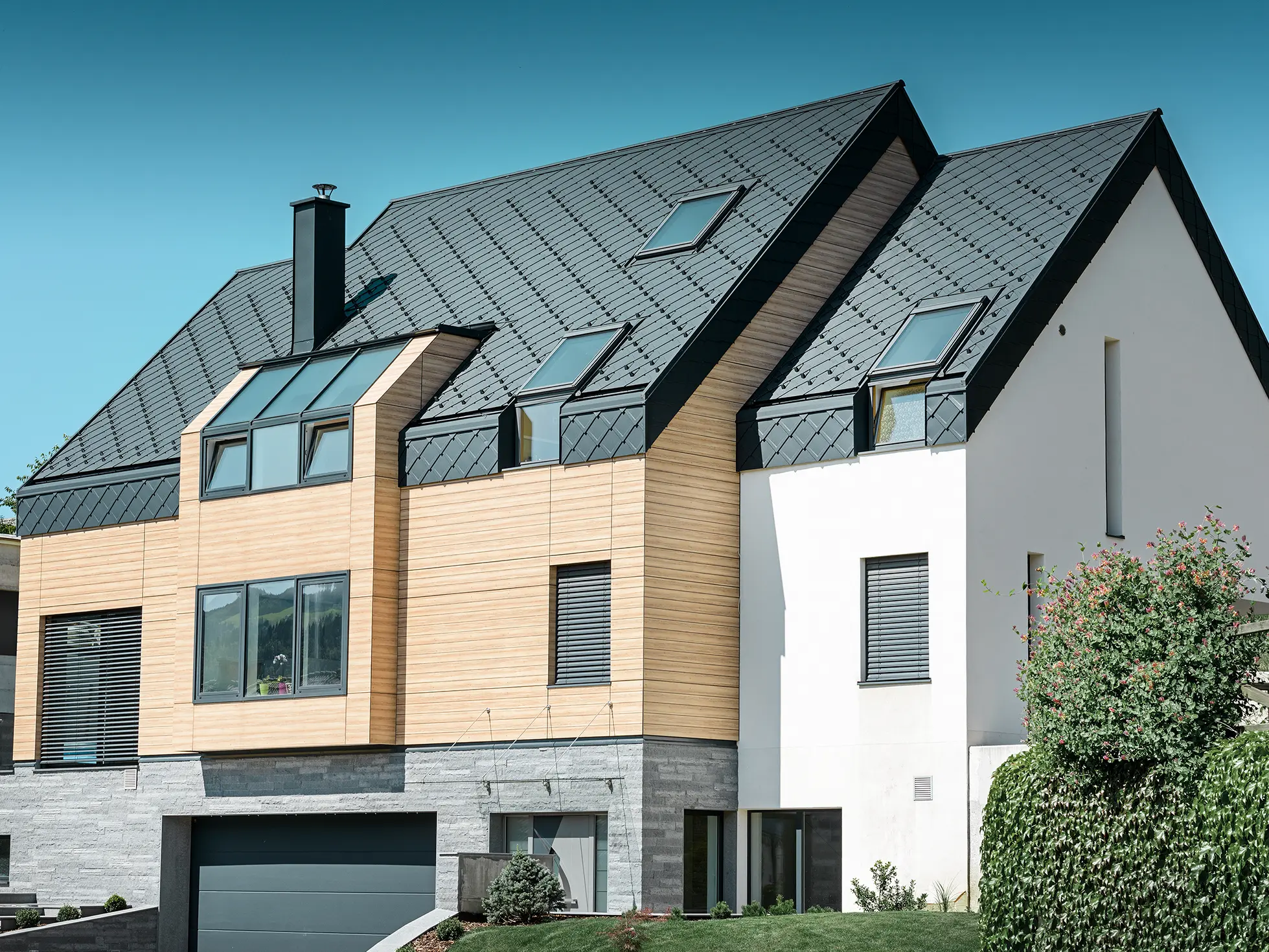 Nouvelle construction moderne avec un toit s’étendant jusqu’à la partie supérieure de la façade. Les losanges de toiture en aluminium couleur anthracite ont été utilisés pour la couverture