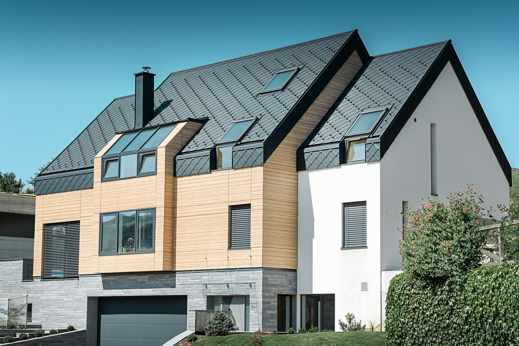 Zeitgemäßer Neubau, bei dem sich die Dachhaut auch über den oberen Teil der Fassade zieht, als Dacheindeckung wurde die Alu-Dachraute in Anthrazit verwendet