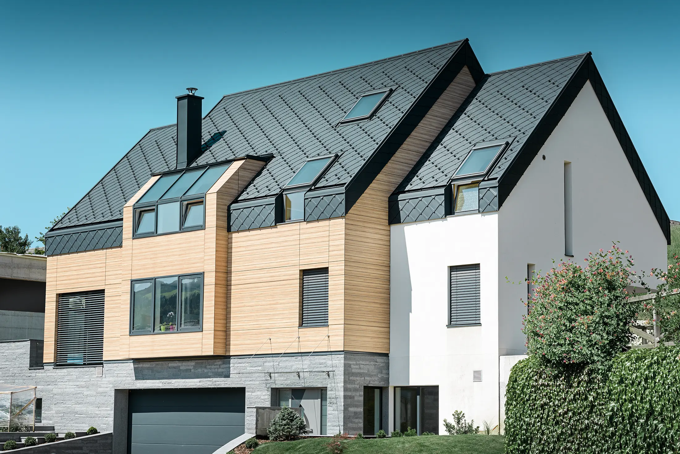 Nouvelle construction moderne avec un toit s’étendant jusqu’à la partie supérieure de la façade. Les losanges de toiture en aluminium couleur anthracite ont été utilisés pour la couverture