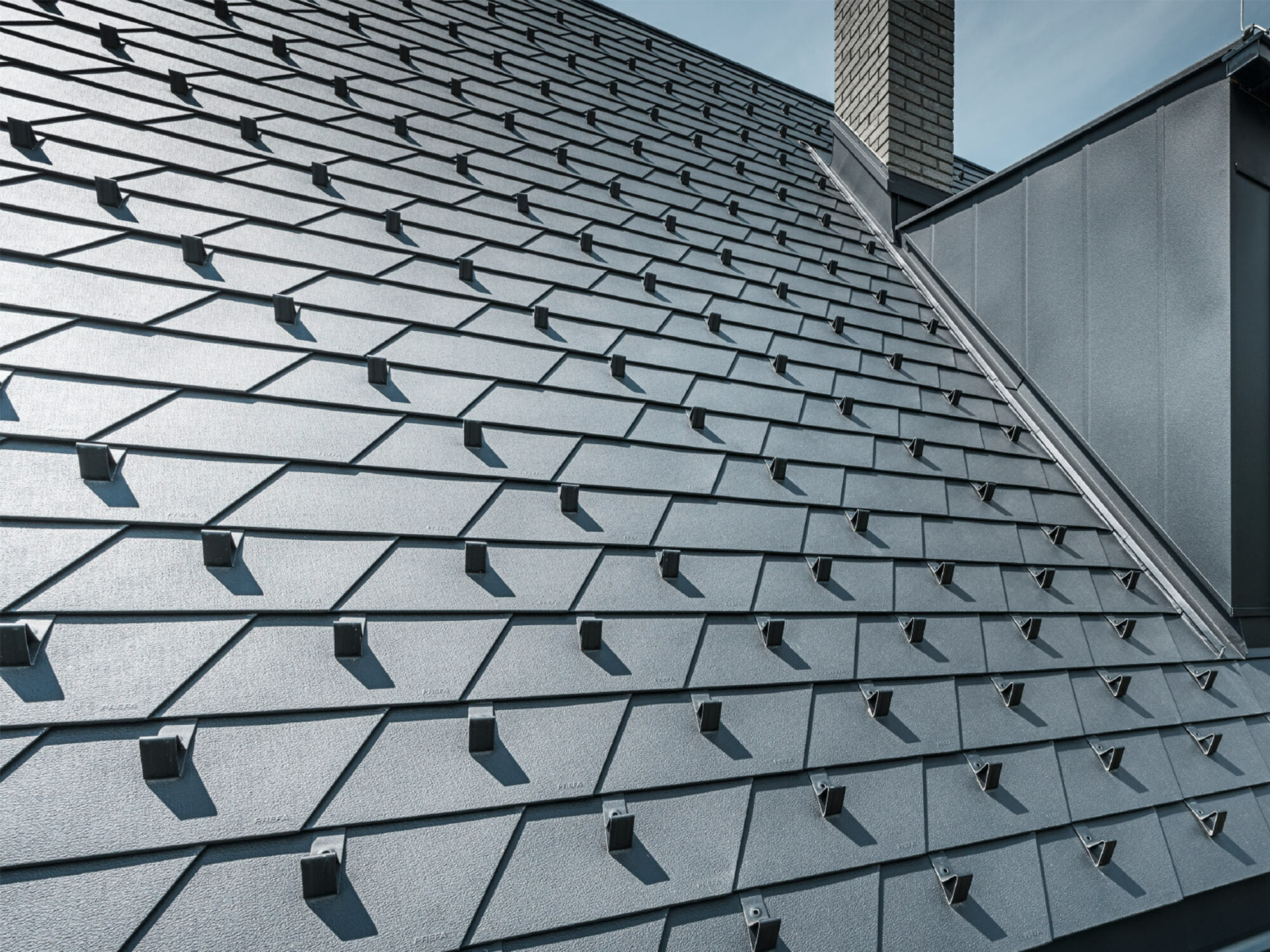 Toit rénové à l'aide de bardeaux de toiture PREFA dans la couleur P.10 noir avec arrêts de neige, lucarne revêtue d'aluminium PREFA