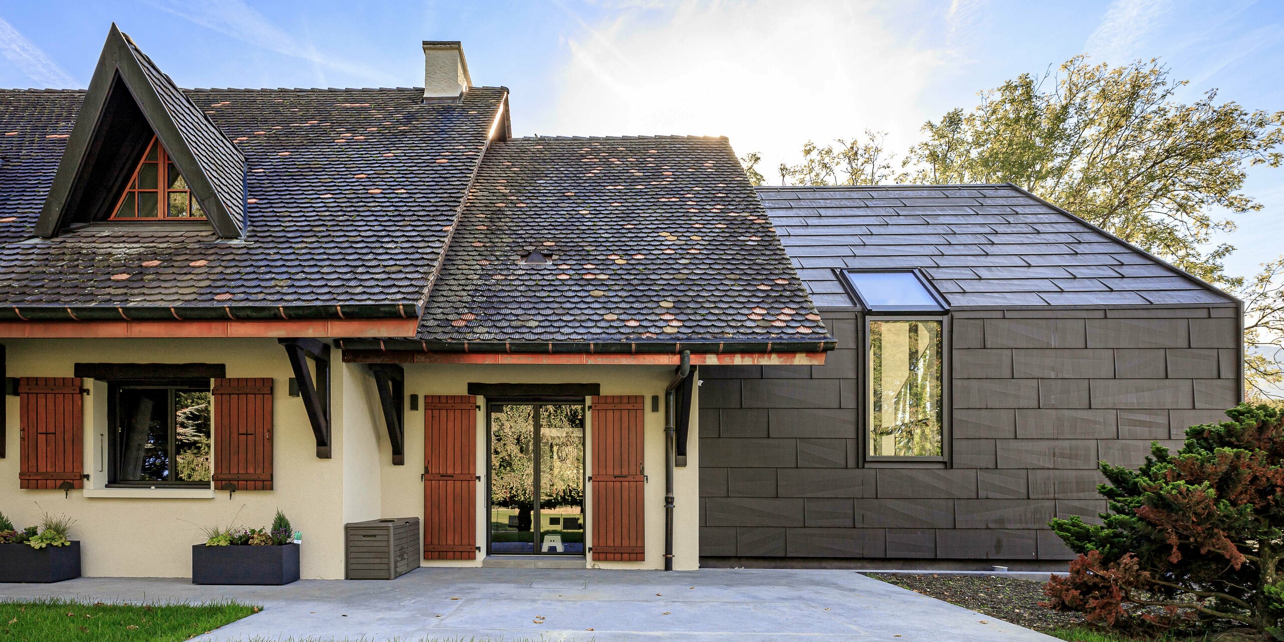 Panneaux de toiture et de façade FX.12 PREFA en P.10 brun comme élément de design contrasté sur l'extension d'une maison individuelle à Lully.