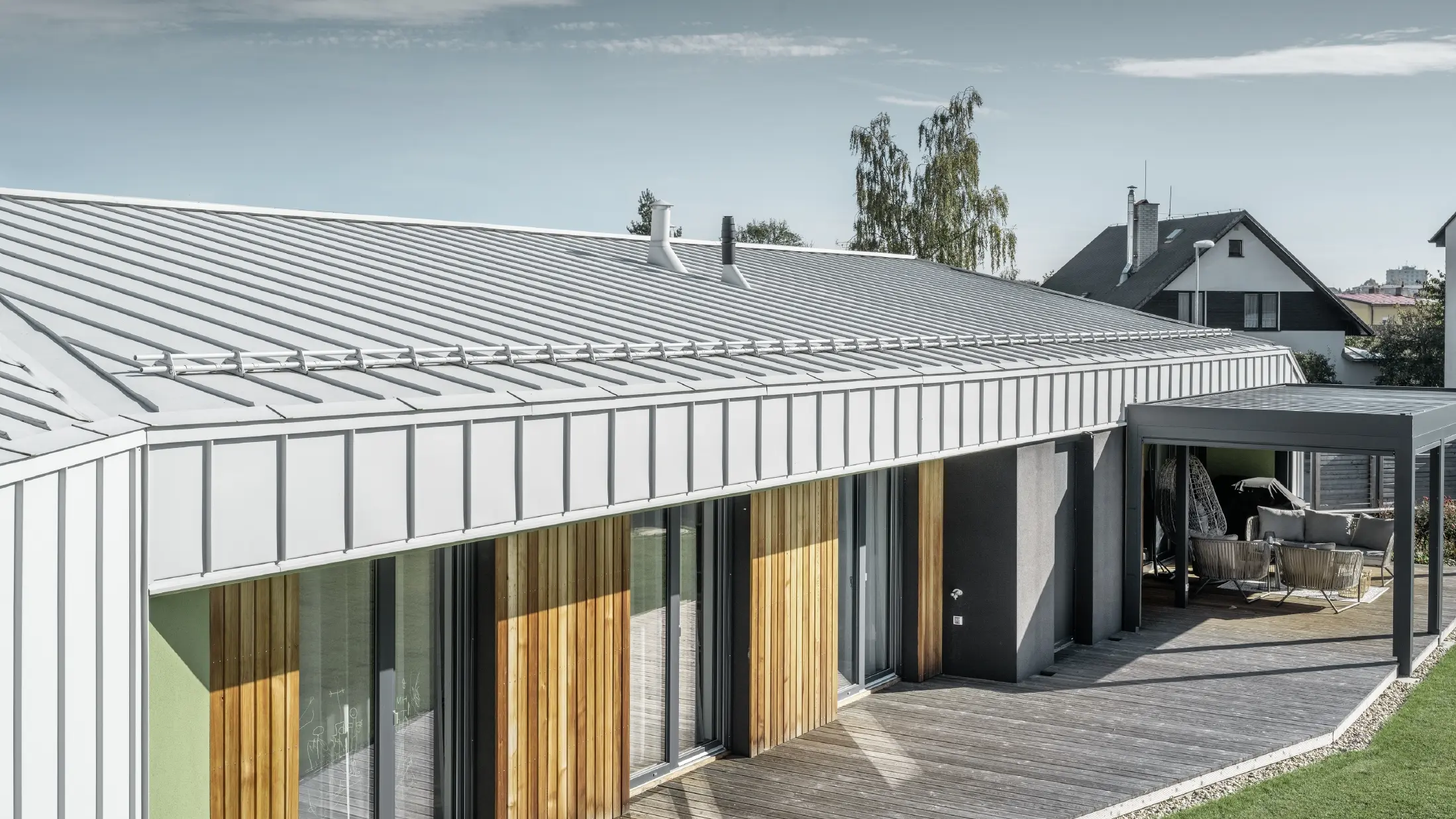Bungalow avec toit et façade PREFALZ couleur blanc Prefa et terrasse en bois