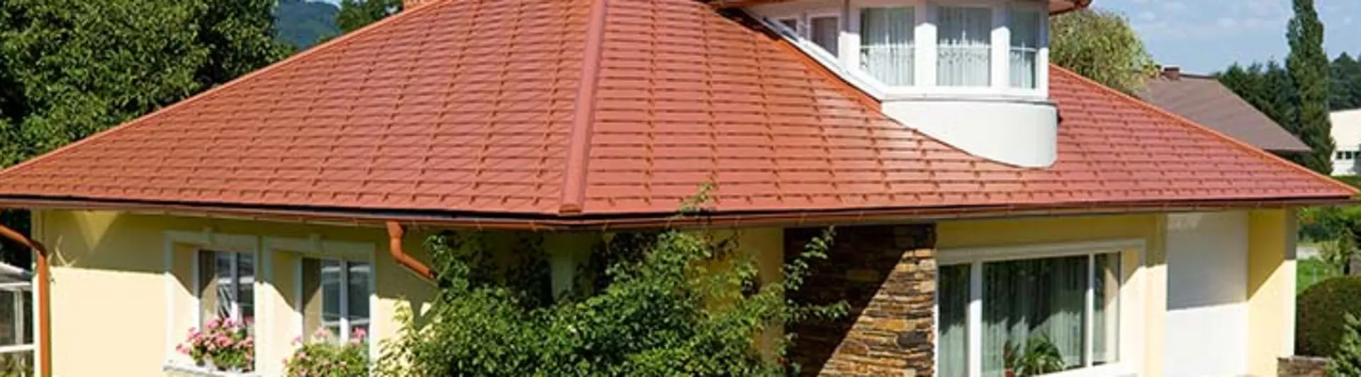 Einfamilienhaus mit Walmdach und Gaube eingedeckt mit der PREFA Aluschindel in Ziegeloptik, Ziegelrot.