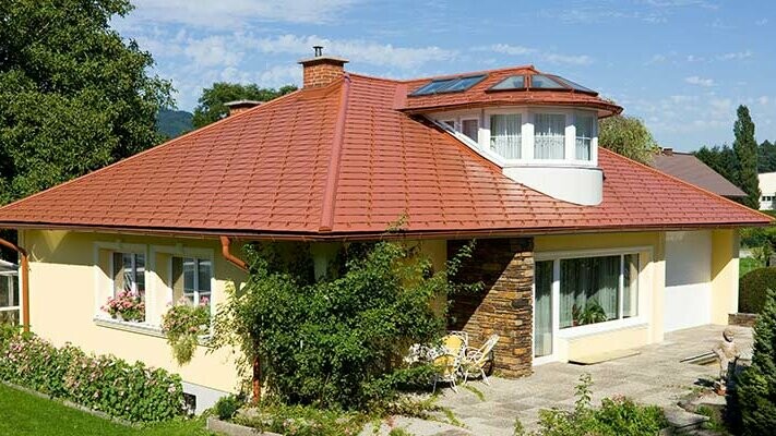 Einfamilienhaus mit Walmdach und Gaube eingedeckt mit der PREFA Aluschindel in Ziegeloptik, Ziegelrot.