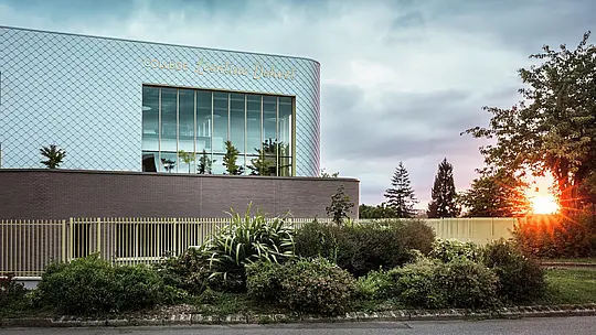 Le collège Léontine Dolivet, à Cesson-Sévigné, se distingue par sa façade en aluminium remarquable, composée d'environ 15 000 losanges PREFA argent métallisé. Sa surface chatoyante reflète la lumière, créant une allure à la fois dynamique et élégante. De larges baies vitrées offrent des vues imprenables sur la verdure environnante, tandis que le système de façade PREFA, robuste et durable, garantit une excellente résistance aux intempéries. L'alliance du métal irisé et des lignes architecturales épurées fait de ce bâtiment un véritable chef-d'œuvre et met en valeur les atouts de l'aluminium : légèreté, absence d'entretien et durabilité.