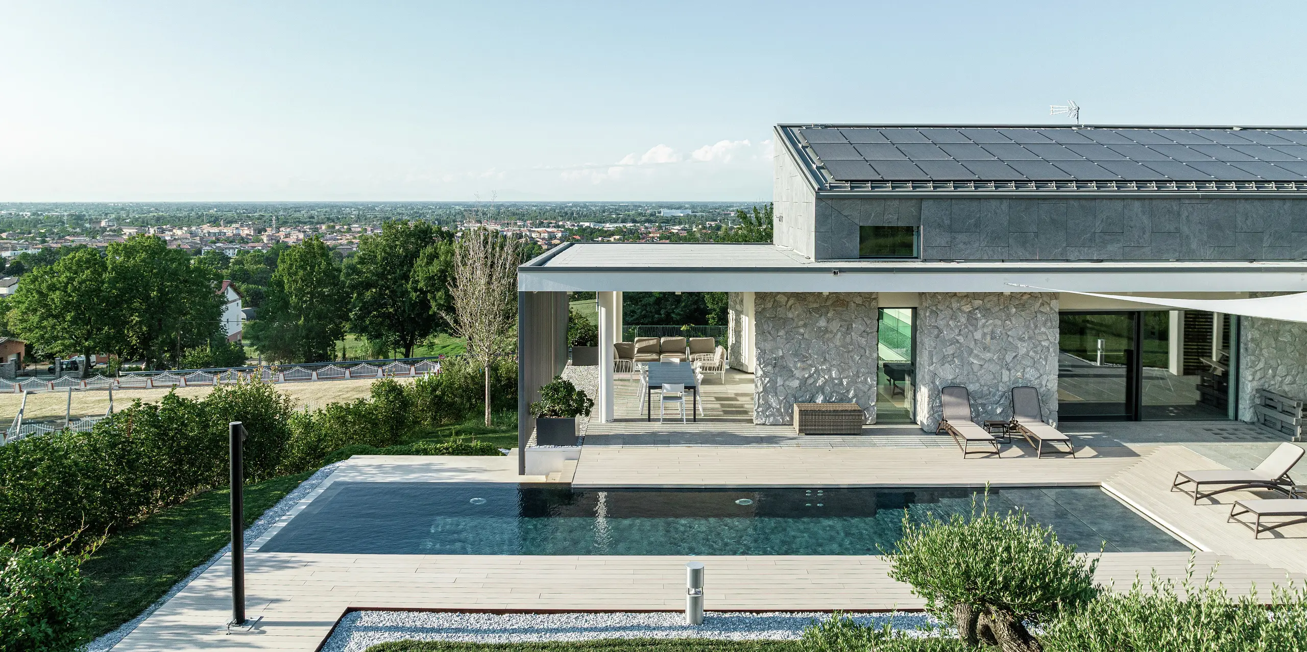 Luxueuse maison individuelle à Scandiano avec des vues panoramiques impressionnantes. Le bâtiment moderne impressionne par sa conception de toit de haute qualité avec PREFALZ en P.10 anthracite. La spacieuse terrasse avec piscine et pergola s'intègre harmonieusement dans le paysage. La solution de toiture durable PREFA protège de manière fiable la maison et lui confère une apparence intemporelle et élégante.