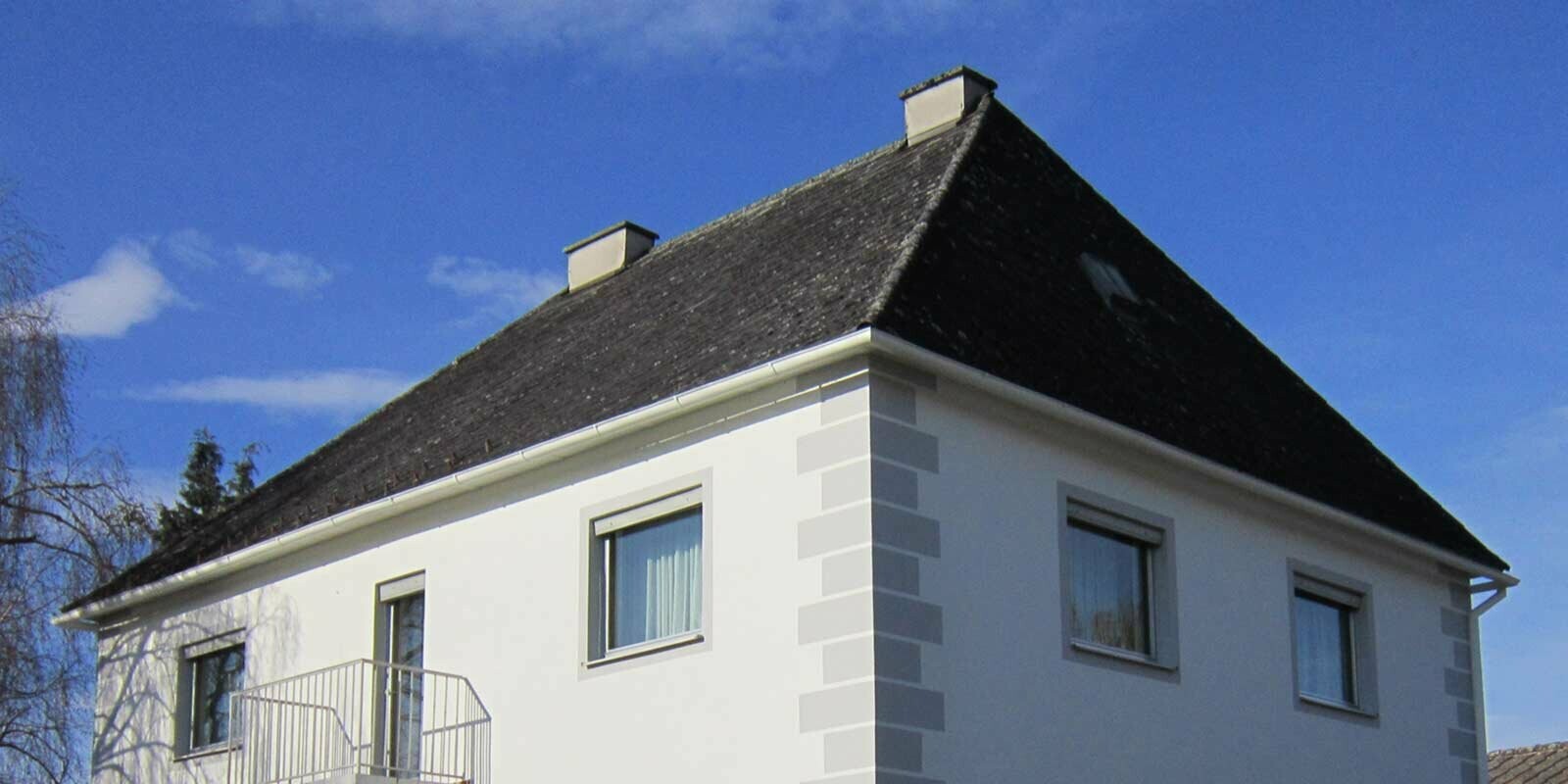 Maison avec toit à croupes avant la rénovation de toiture à l’aide de Prefalz et de tuiles PREFA, en Autriche