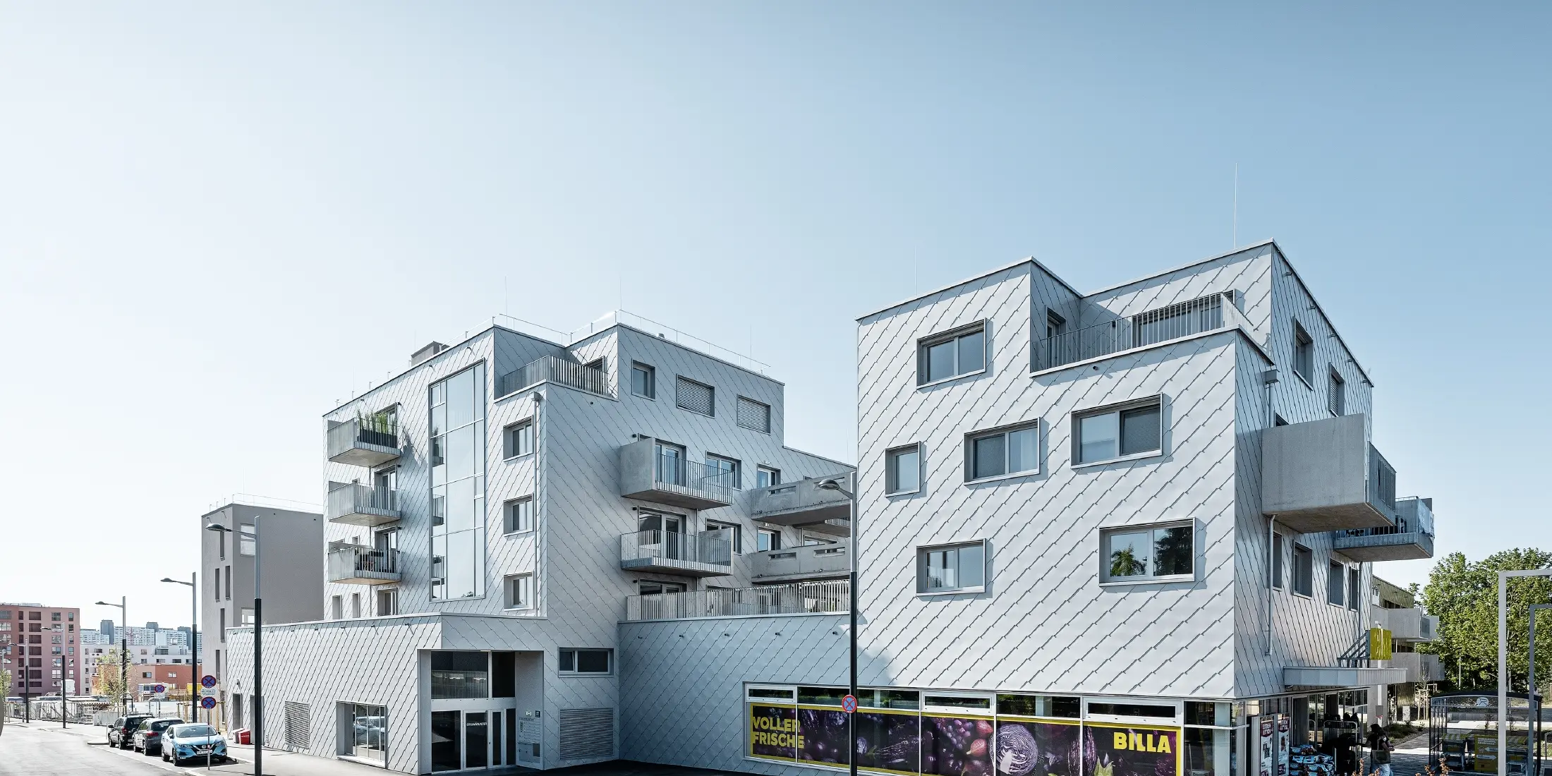 Complexe résidentiel à toit plat recouvert de losanges de façade 44 × 44 PREFA en argent métallisé.