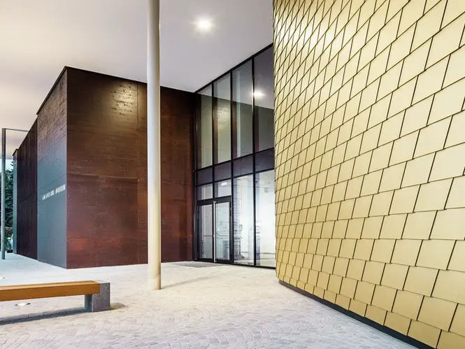 Prise de vue rapprochée de l'école de musique régionale de BUchkirchen. La façade a été recouverte des bardeaux PREFA dans la teinte spéciale Maya Gold.