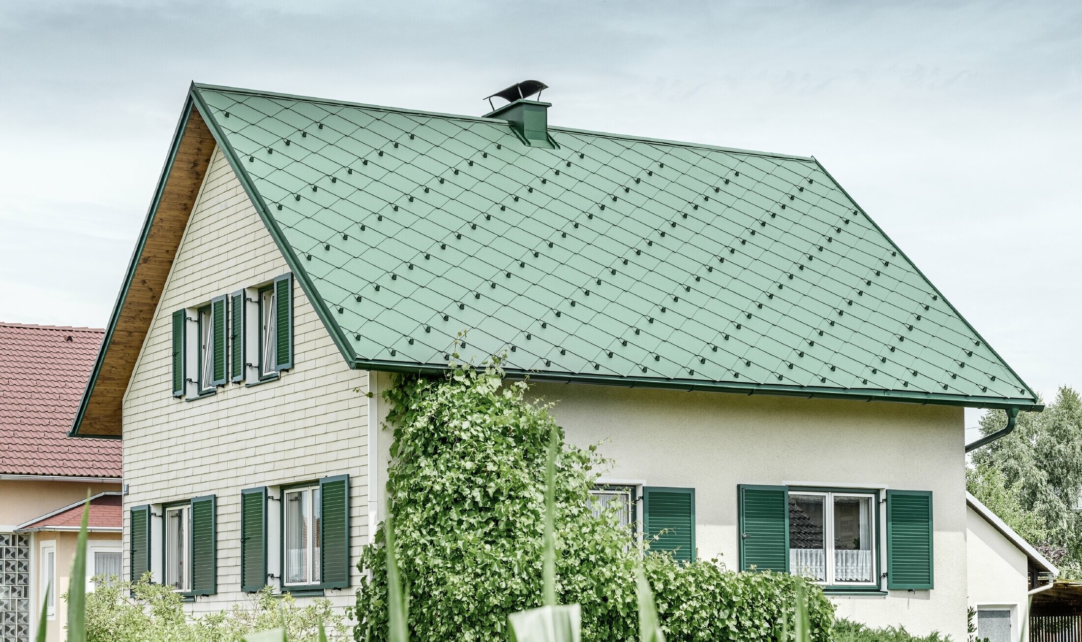 Toit à pignon de maison individuelle classique avec couverture en aluminium vert mousse et volets verts