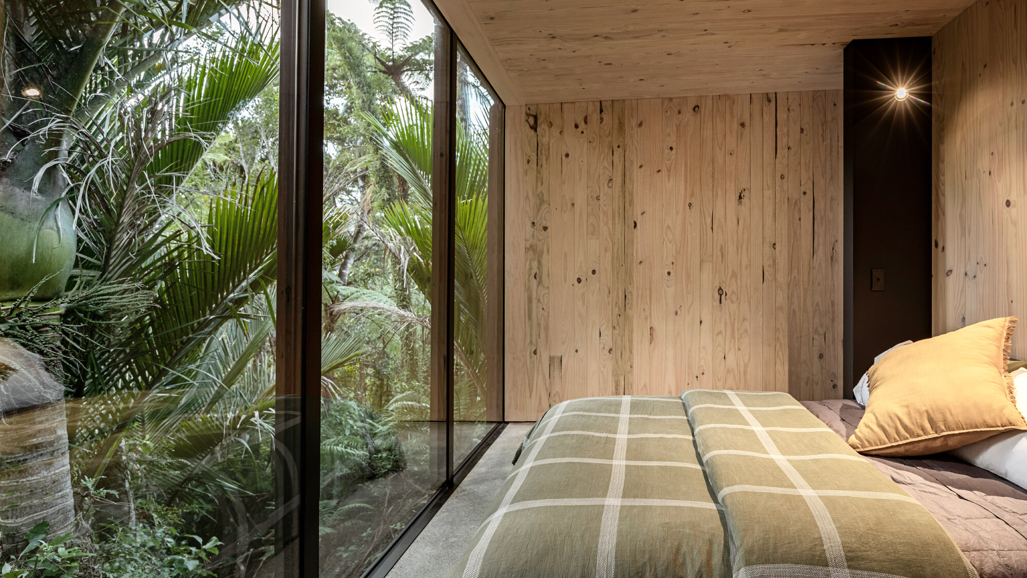 Das Schlafzimmer mit dem bodentiefen Fenster, an das der Urwald direkt anschließt.