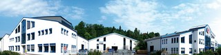 Panoramaaufnahme des PREFA Standorts in Wasungen, Deutschland; weißes Gebäude mit blauen Fenstern