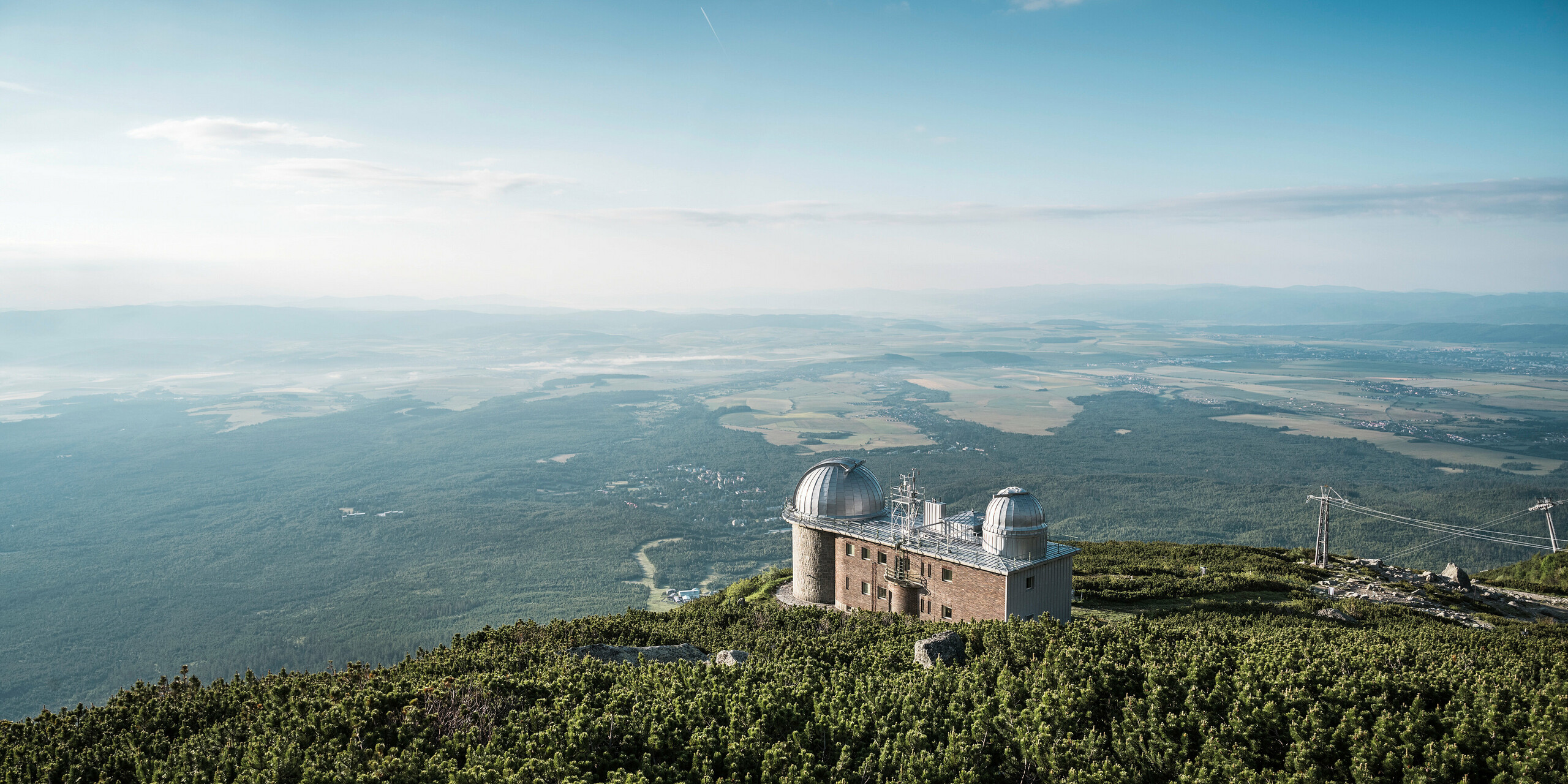 Úchvatné daleké výhledy na hvězdárnu Skalnaté Pleso, která se nachází v nadmořské výšce 1 783 m, obklopená klidnou nádherou Vysokých Tater na Slovensku. Dvě charakteristické kopule pokryté lesklým PREFALZ ve stříbrné metalíze odrážejí rozlehlost oblohy a ladí s přírodou. Hvězdárna představuje nejen astronomickou dokonalost, ale také odolnost a ekologickou sílu společnosti PREFA, jejíž hliníkové produkty poskytují ochranu a odolnost i v této vzdálené nadmořské výšce, podpořenou komplexní 40letou zárukou.