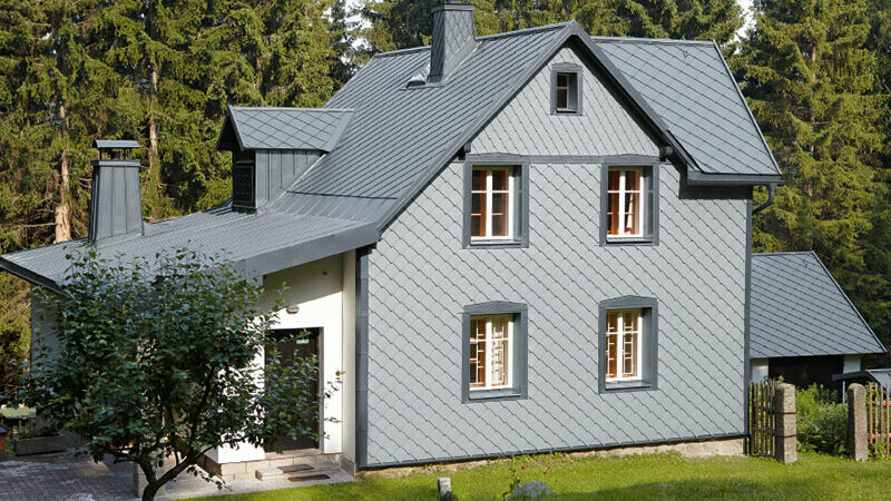 Einfamilienhaus in Waldlage mit witterungsbeständiger PREFA Aluminiumfassade in Hellgrau.