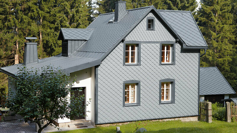 Maison individuelle dans un espace boisé avec façade en aluminium PREFA résistante aux intempéries en gris souris.