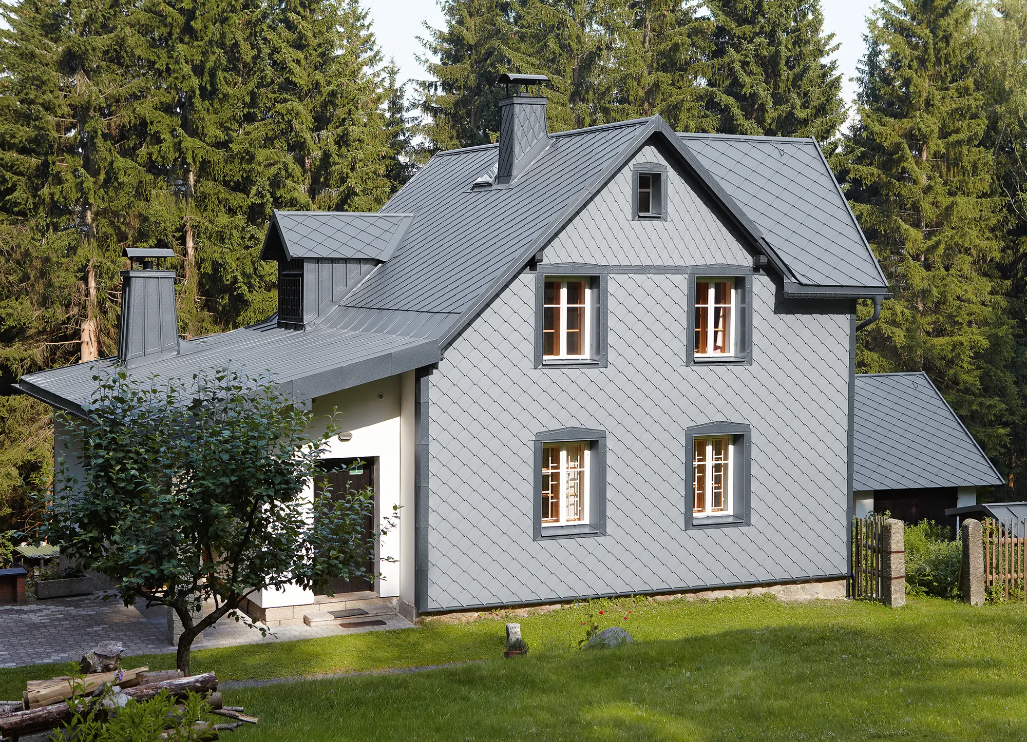 Maison individuelle dans un espace boisé avec façade en aluminium PREFA résistante aux intempéries en gris souris.