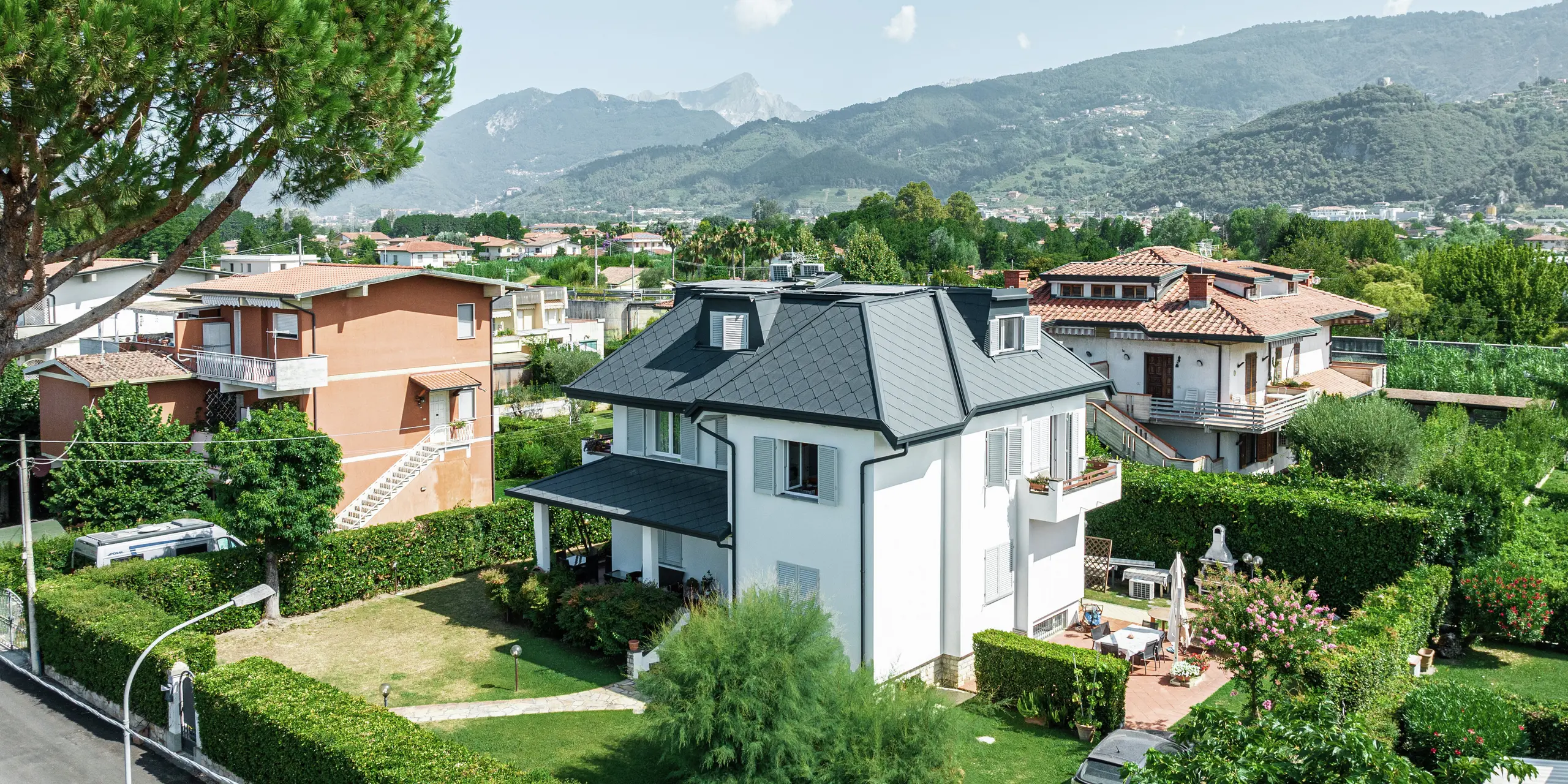 L'élégante maison individuelle de Montignoso, en Italie, impressionne par sa toiture PREFA de haute qualité en aluminium robuste. Le toit en losanges PREFA 44 × 44 en P.10 gris pierre offre une solution moderne, résistante aux intempéries et durable. La toiture en aluminium s'intègre harmonieusement dans l'environnement méditerranéen et offre une protection optimale contre les tempêtes, la corrosion et les rayons UV. La finition précise et le design élégant soulignent la haute qualité des produits PREFA.
