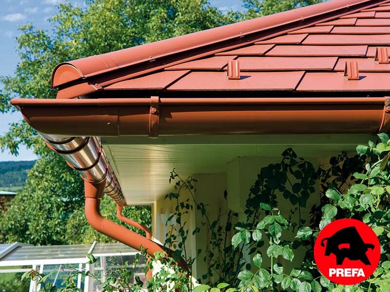 Einfamilienhaus mit Walmdach und Gaube ingedeckt mit der PREFA Aluschindel in Ziegeloptik, Ziegelrot