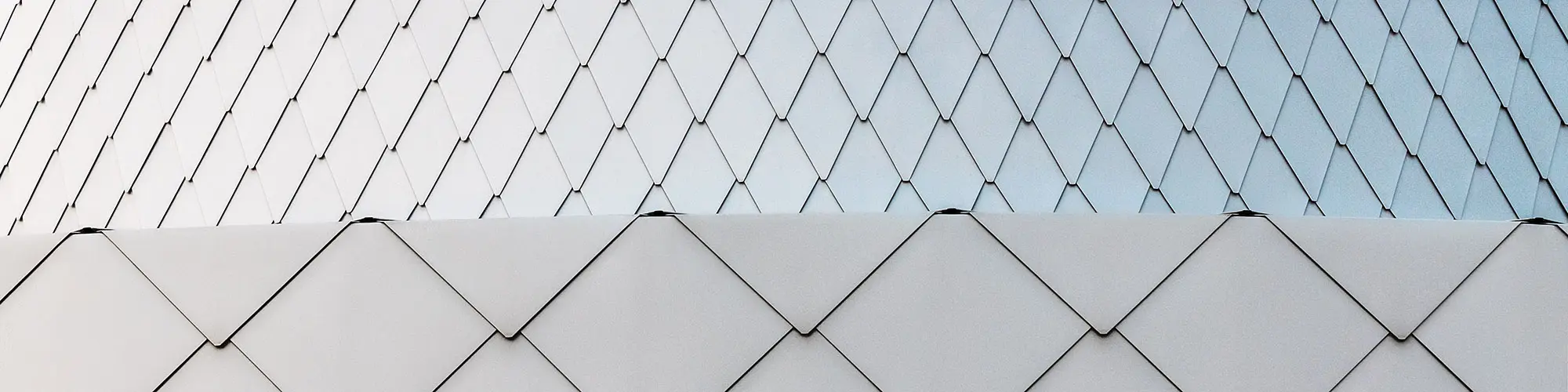 Prise de vue rapprochée de la façade en losange PREFA dans la teinte argent métallisé, dont la pose est très précise au niveau des angles. L'ensemble créé une impression d'homogénéité. 