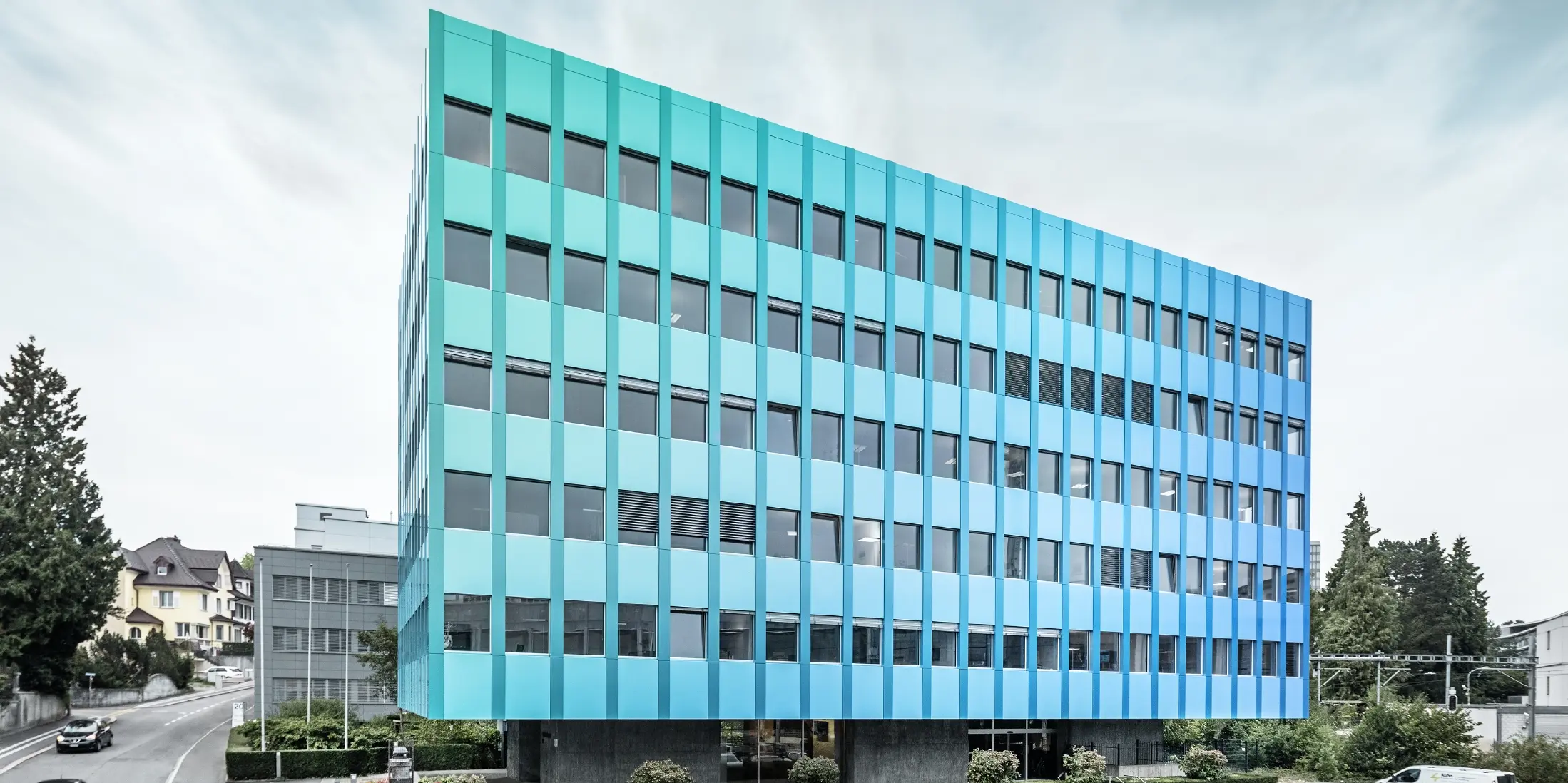 Vue latérale de la maison Wieland à Aarau ; la façade est revêtue de panneaux composites PREFABOND en aluminium de PREFA, qui brillent d'un éclat bleu-vert grâce à un procédé de revêtement spécial.