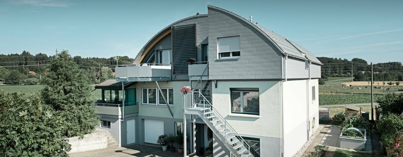 Bâtiment d’habitation avec toit en berceau couvert de tuiles et Prefalz PREFA couleur P.10 gris souris