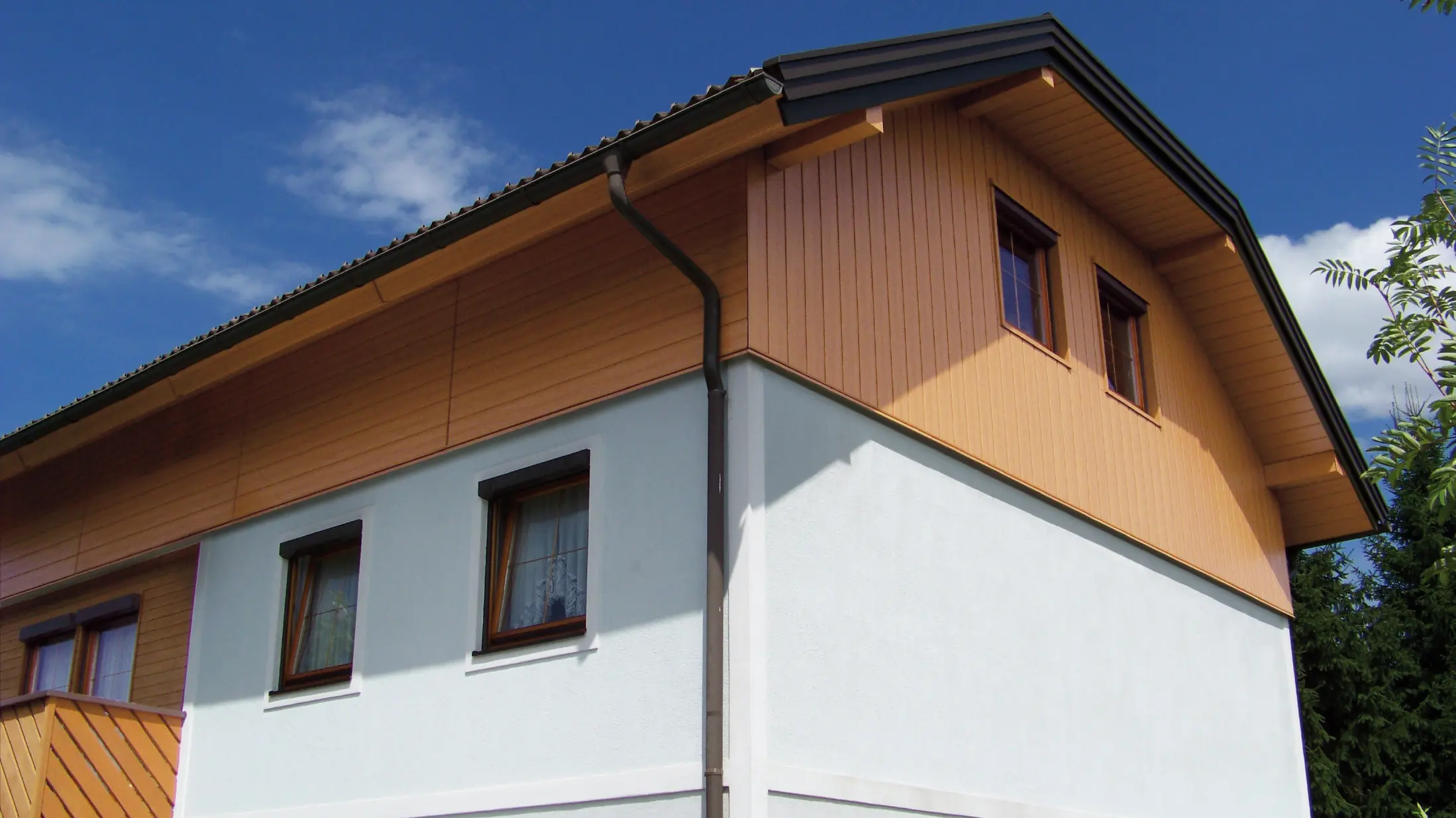 Grande maison individuelle à toit à demi-croupe et revêtement des pignons avec des Sidings PREFA imitation bois clair