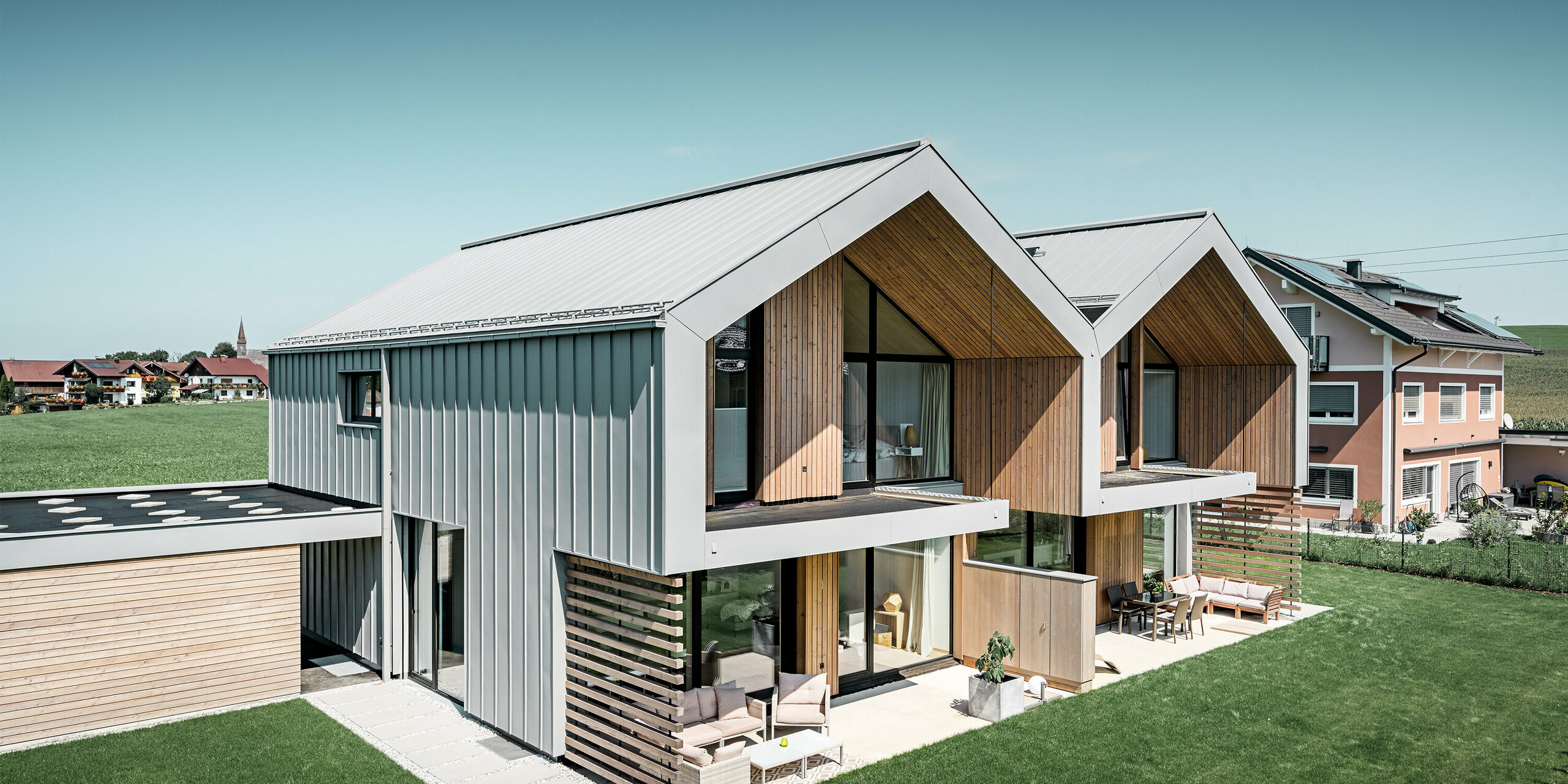 moderne Doppelhäuser mit PREFALZ Gebäudehülle, Dach und Fassade sind mit PREFALZ in Patina grau verkleidet inkl. Quadratrohr