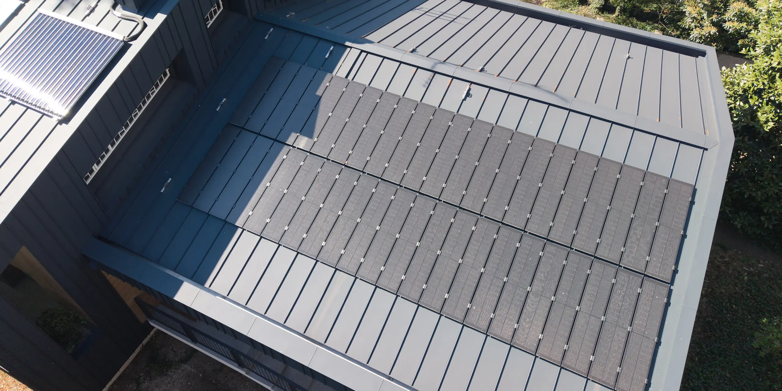 Detailaufnahme des PREFALZ Aluminiumdachs der Villa Castellanza in P.10 Anthrazit mit eleganten PREFALZ Solarmodulen. Die großflächige Solarlösung fügt sich nahezu nahtlos in die moderne Dachlandschaft ein und verbindet anspruchsvolle Architektur mit nachhaltiger Energiegewinnung. PREFA Aluminium überzeugt durch Langlebigkeit, Witterungsbeständigkeit und ein harmonisches Gesamtbild.