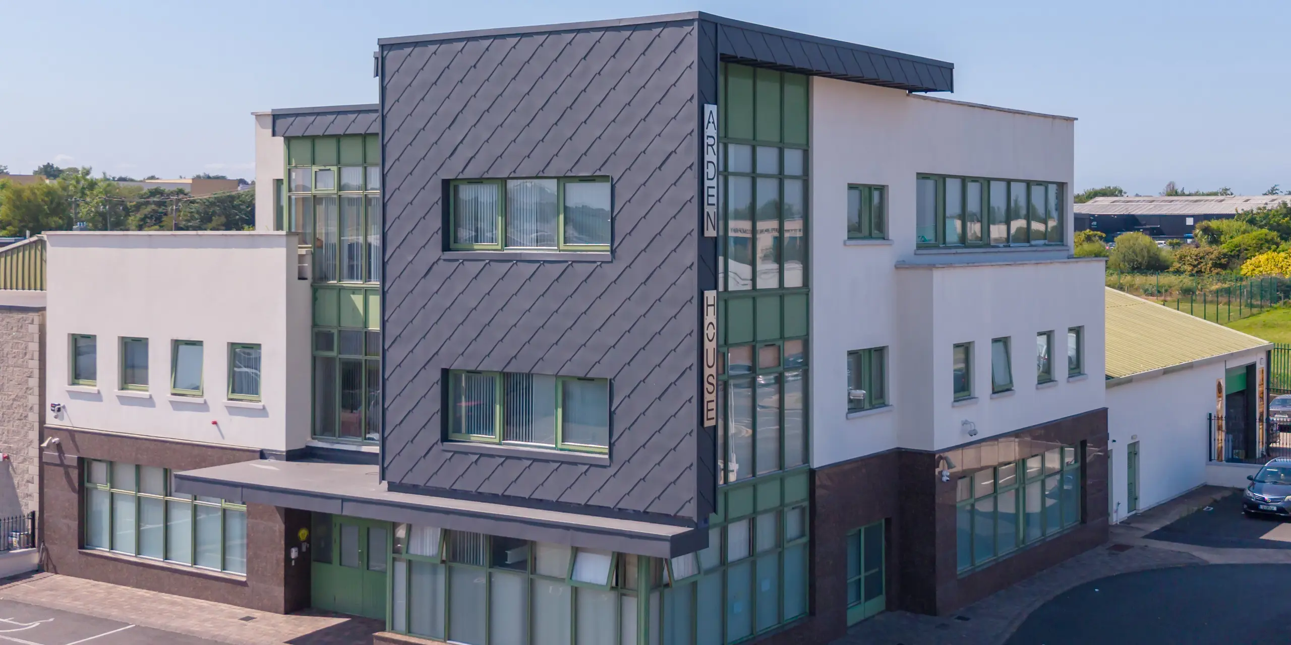 L'imposant bâtiment cubique d'Arden House, un centre de santé mentale pour enfants et jeunes situé à Wexford, est revêtu de losanges de façade 44x44 PREFA couleur P.10 gris sombre. La structure dynamique en losanges souligne la pureté des lignes architecturales, tandis que les fenêtres vertes apportent une touche d'originalité. La façade en aluminium, durable et résistante à la corrosion, offre un entretien minimal et une grande robustesse.