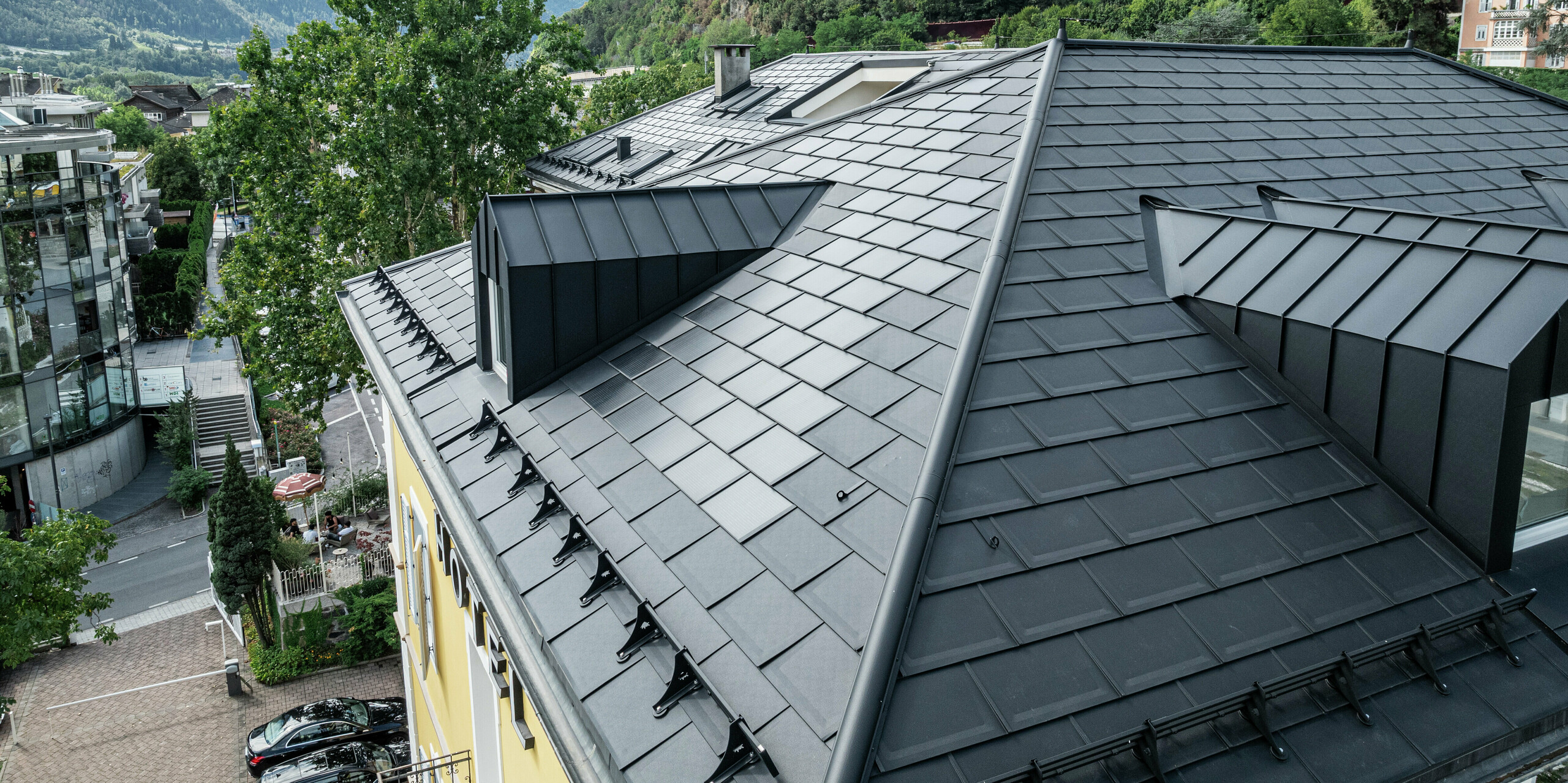 Le toit PREFA de l'hôtel Jarolim à Bressanone impressionne par ses tuiles solaires PREFA innovants et ses R.16 en P.10 noir moderne. Les lucarnes et autres détails du toit ont été réalisés avec précision, de sorte que fonctionnalité et esthétique soient parfaitement combinées. Le toit en aluminium durable et résistant aux intempéries est idéal pour les bâtiments classés et permet une production d'énergie durable sans compromettre l'aspect historique. La maison historique impressionne par sa qualité et son innovation au plus haut niveau.
